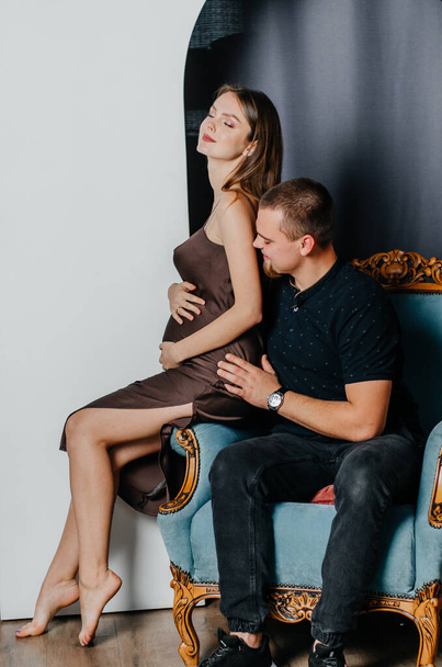 eine schwangere Frau und ein Mann sitzen auf einem Stuhl - Foto, Bild