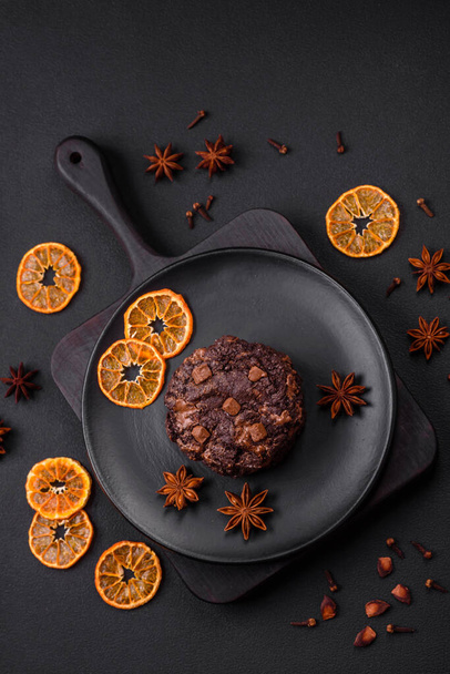 Deliciosas galletas redondas de avena fresca con chocolate en un plato de cerámica negra sobre un fondo de hormigón oscuro - Foto, imagen