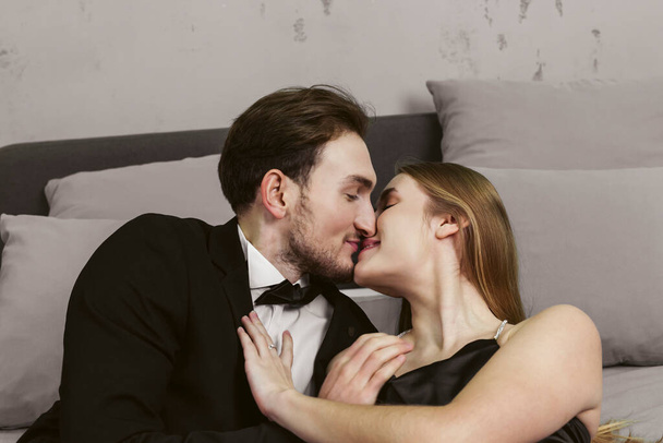 Una giovane coppia felice in abiti eleganti coccole e baci sullo sfondo di una stanza industriale. - Foto, immagini