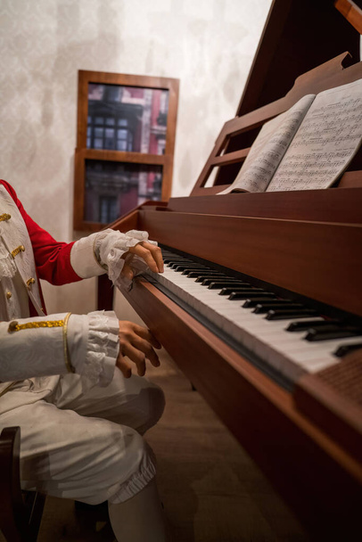 ピアノを身に着けていた17世紀の伝統的なロココ様式の衣装を着た男の手. - 写真・画像