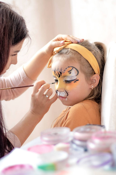 childrens makeup face paint drawings Girls face painting. Little girl having face painted on birthday party. closed eyes. High quality photo - Fotó, kép