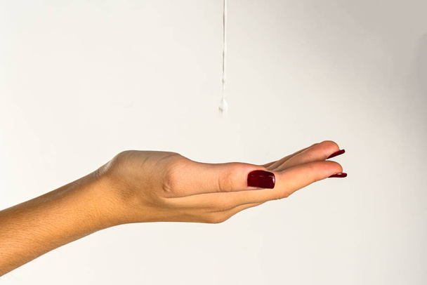 mani di una giovane donna gocciolante acqua limpida, sfondo bianco - Foto, immagini