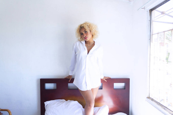 bela latina jovem em pijama de pé em sua cama - Foto, Imagem
