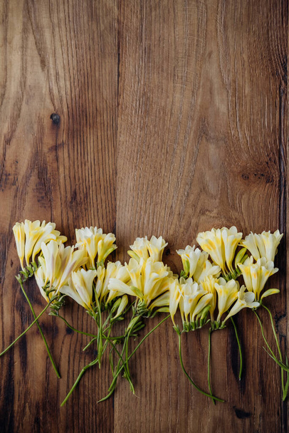 Vista superior sobre hermoso fondo rústico de primavera floral con flores de freesia amarillas y espacio de copia, plano.  - Foto, imagen