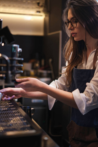 Barista de pie en una cafetería y haciendo espresso en una máquina de café. - Foto, Imagen