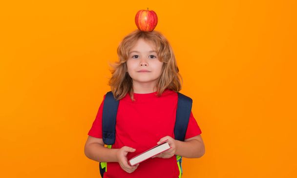 Smart child, clever school kid. School boy, isolated on yellow studio background. Back to school. Apple on head, idea concept - Fotografie, Obrázek