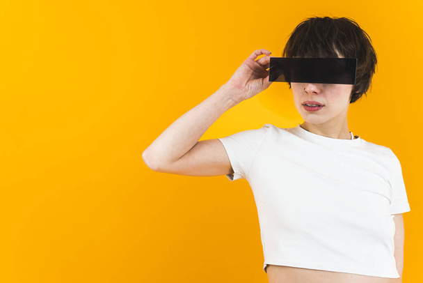 Bright orange background. Woman putting a black strip to her eyes. Medium shot. High quality photo - Fotografie, Obrázek