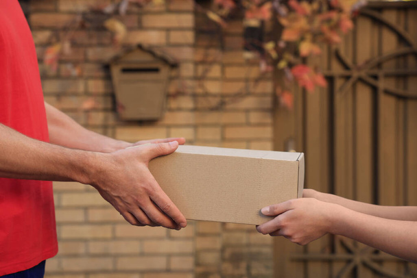 Man receiving parcel from courier outdoors, closeup - Fotó, kép