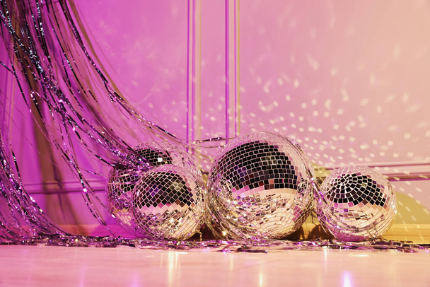 Shiny disco balls and foil fringe curtain indoors, color toned - Foto, afbeelding