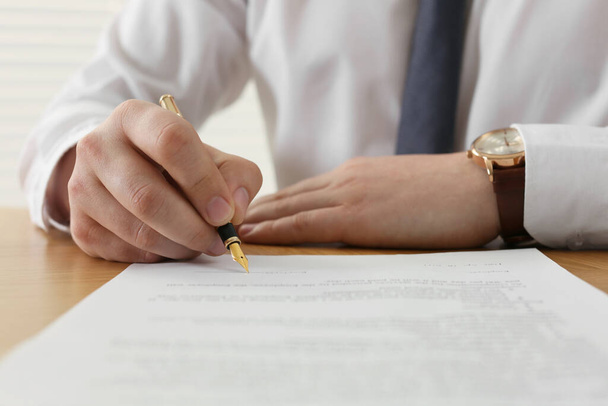 Notary signing document at wooden table, closeup - 写真・画像