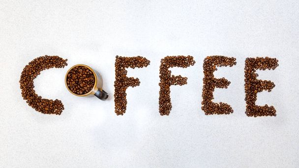 Καφές γραμμένο με κόκκους καφέ. Καφές σκούρα φασόλια ψητό συλλαβίσει γραπτή λέξη φόντο. Αντιγραφή κειμένου χώρο και καφέ σε λευκό πάγκο κουζίνας ταπετσαρία - Φωτογραφία, εικόνα