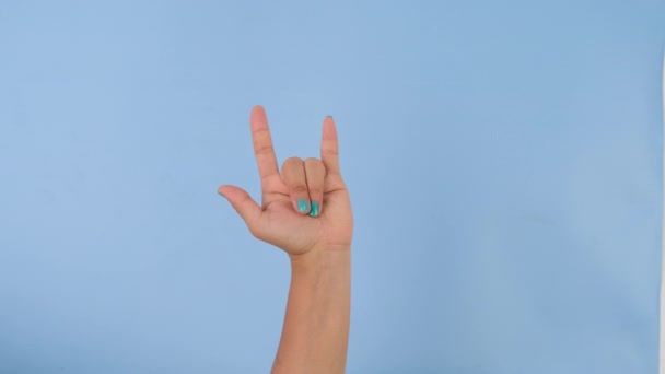 Vrouwelijke hand met I Love You teken geïsoleerd op pastelblauwe achtergrond in de studio. Pakket van gebaren bewegingen en lichaamstaal. Liefde handteken - Video