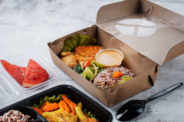 Lunch box with brown rice, chicken curry and vegetables.Tasty and healthy lunch box. - Foto, afbeelding