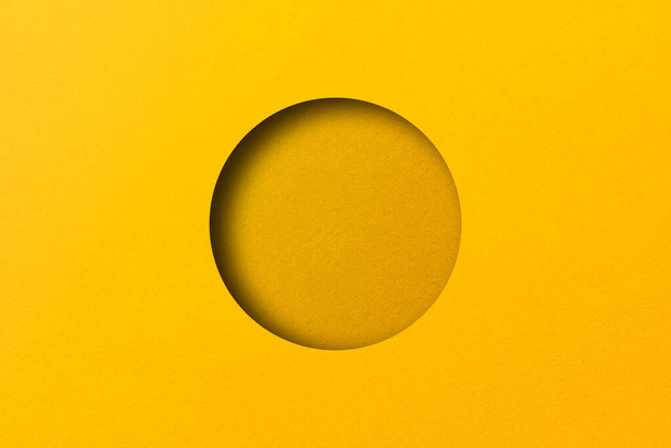 Sarı kağıt dairesel deliklere bölünmüş ışık ve gölgelerle dolu.. - Fotoğraf, Görsel
