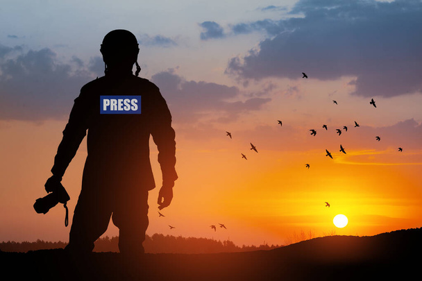 Photojournalist silhouette documenting war or conflict. Photojournalist at sunset. War, army, technology and journalist work concept. - Foto, Imagen