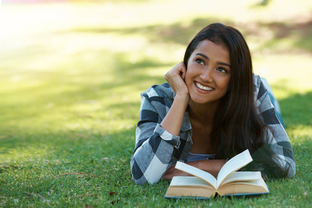 Entspannen mit einem guten Buch. eine junge Frau, die im Gras liegt und ein Buch liest - Foto, Bild