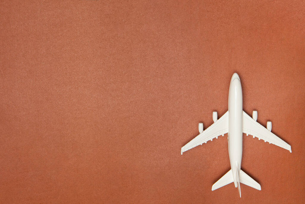 Uçak modeli. Kahverengi arka planda beyaz uçak. Seyahat tatili konsepti. Yaz dönemi. Düz konum, üst görünüm, kopyalama alanı. - Fotoğraf, Görsel
