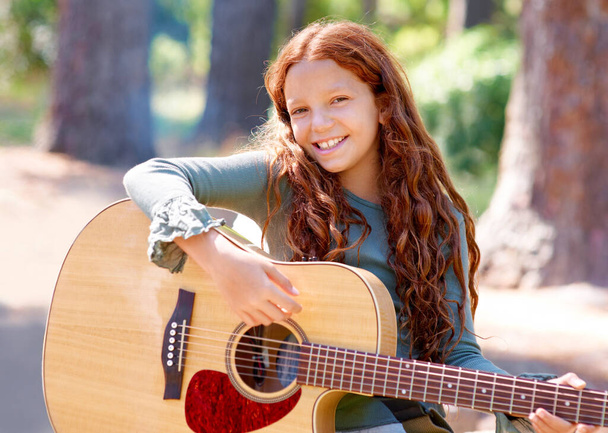 Poprawiając jej umiejętności gitarowe. Młoda dziewczyna gra na gitarze na świeżym powietrzu - Zdjęcie, obraz