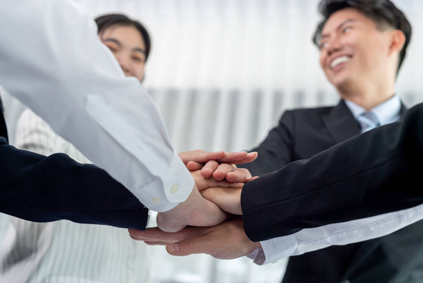 Bottom view partial hands wearing formal suit joining stack as symbol of team building, unity and harmony in office workplace. Successful business team of synergy holding hand together - Photo, Image