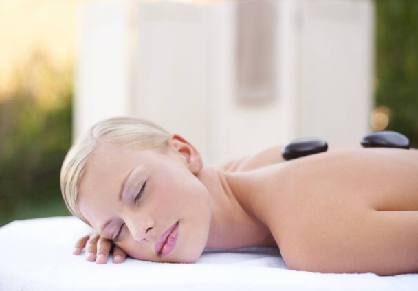 Пусть ваши заботы растают... молодая женщина получает расслабляющий массаж горячими камнями в спа - Фото, изображение