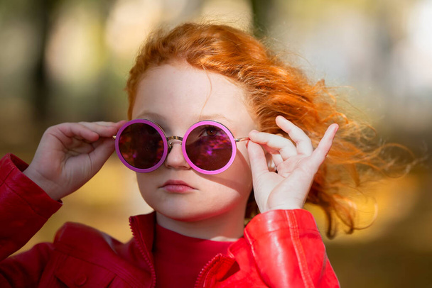 Mor yuvarlak güneş gözlüklü, kızıl saçlı şık bir kızın portresi.. - Fotoğraf, Görsel