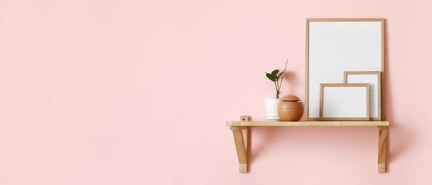 Blank photo frames, air freshener and houseplant on shelf hanging on light pink wall. Banner for design - Fotografie, Obrázek