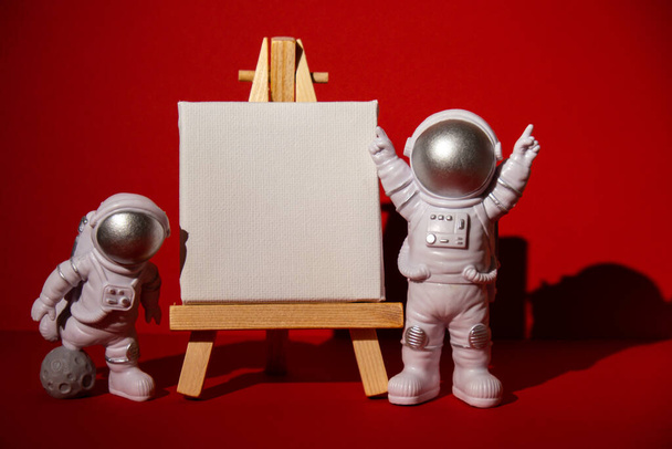 Kağıt not şablonuna sahip plastik oyuncak astronot renkli kırmızı arkaplan kopyalama uzayı metniniz için modelleme yapın. Dünya dışı seyahat kavramı, özel uzay adamı ticari uçuşları. Uzay görevleri ve - Fotoğraf, Görsel