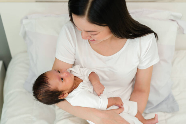 mother holding and talking with her newborn baby on a bed - Foto, Bild