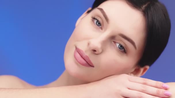 Young healthy brunette woman smile and touching smooth skin on face, beauty skincare concept. Skincare treatment, cosmetics and anti age plastic surgery. Face lifting, cosmetics. Model with blue eyes and perfect clean fresh skin looking at camera - Footage, Video