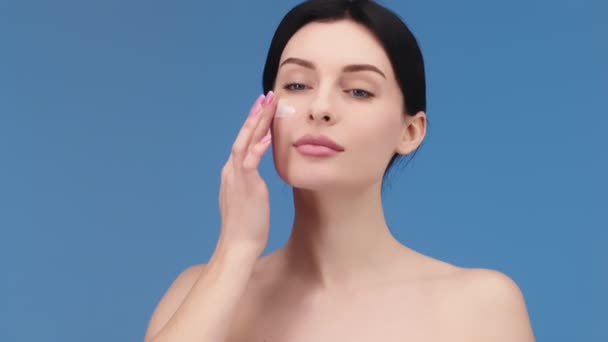 Çekici Avrupalı genç bir kadının geniş bir yakın çekimi bir pipetten yanağına yüz bakımı serumu uyguluyor. Yüz serumu reklamı - Video, Çekim