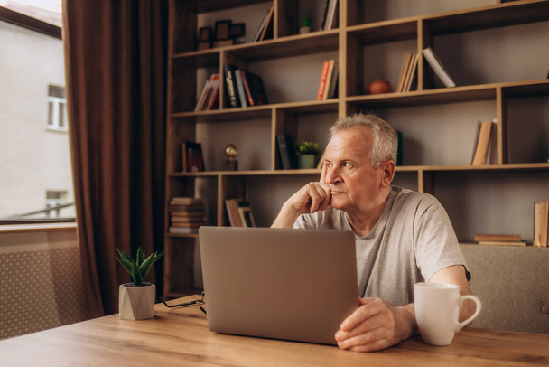 Uomo anziano a casa collegato sul computer portatile
 - Foto, immagini