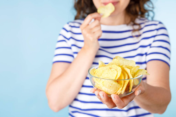 Woman on diet can't resist craving to eat potato chips. Food addiction, diet breakdown, compulsive overeating concept - Foto, Imagen