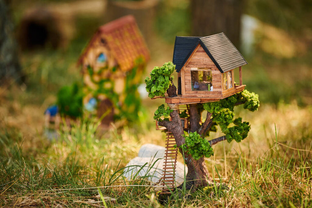 Little dollhouse on front lawn, cute small decorative house on green grass field, environment concept. Forest small doll house in green grass, charming garden decoration for home lawn, - Photo, Image