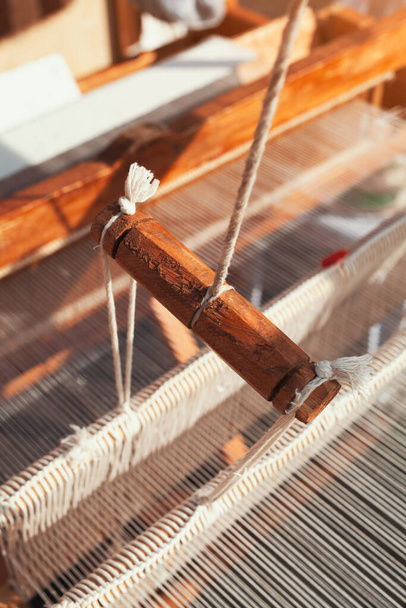 Деталь ткацького обладнання на антикварному дерев'яному ткацькому верстаті та нитковому ткацькому човні. Вироби з текстильної тканини плетіння традиційними інструментами
. - Фото, зображення