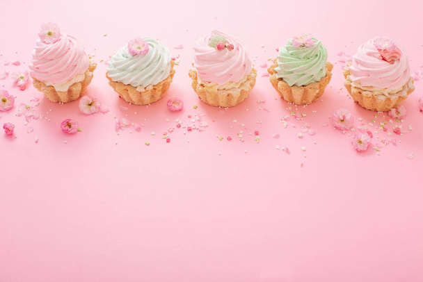 rosa und grüne Cupcakes mit Frühlingsblumen auf rosa Hintergrund - Foto, Bild