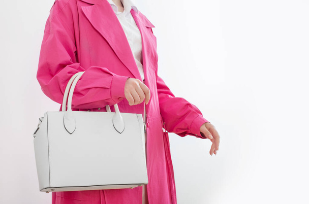 woman in pink trench coat with white handbag - Fotoğraf, Görsel