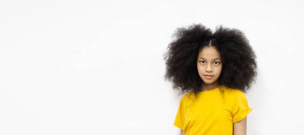 Portret gelukkig meisje met afro kapsel dragen gele T-shirt kijken naar camera witte achtergrond. schattig kind vrouwelijk model mensen mode schoonheid. Kopieerruimte. - Foto, afbeelding