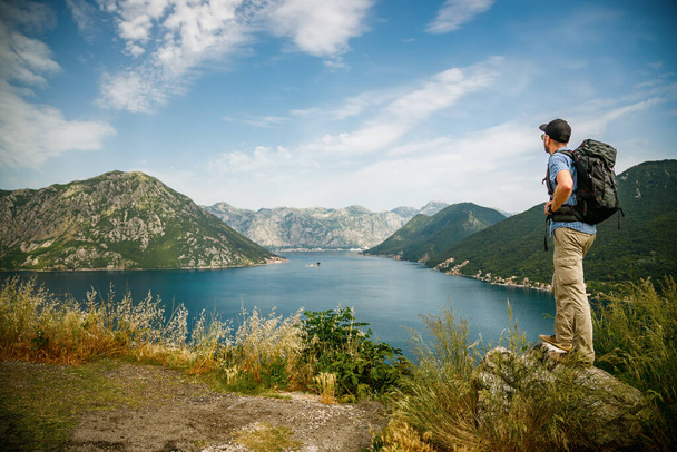 Tourist man standing on the edge of a cliff, enjoying amazing sea view of the Bay of Kotor, Montenegro - Foto, Imagem