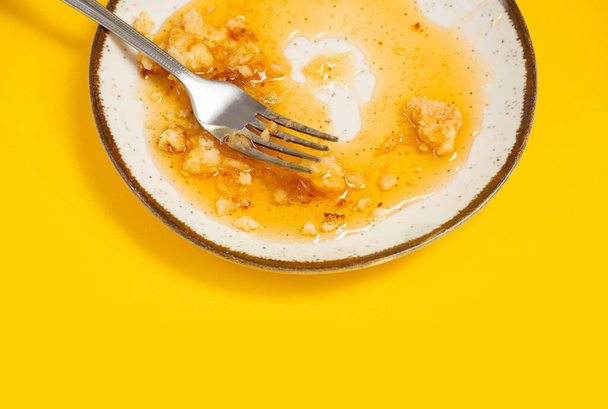 dirty plate with honey and pie crumbs on yellow background - Foto, afbeelding