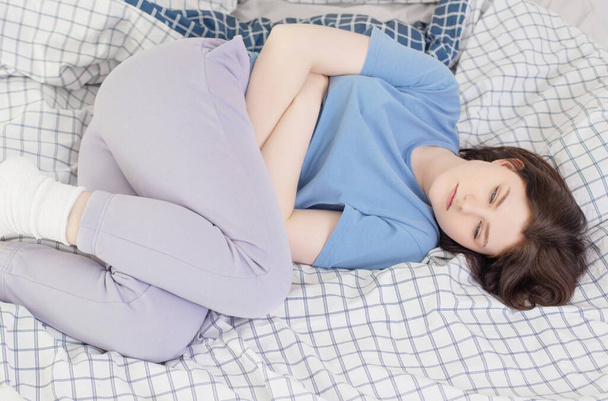 teen girl with stomachache on bed - Photo, image