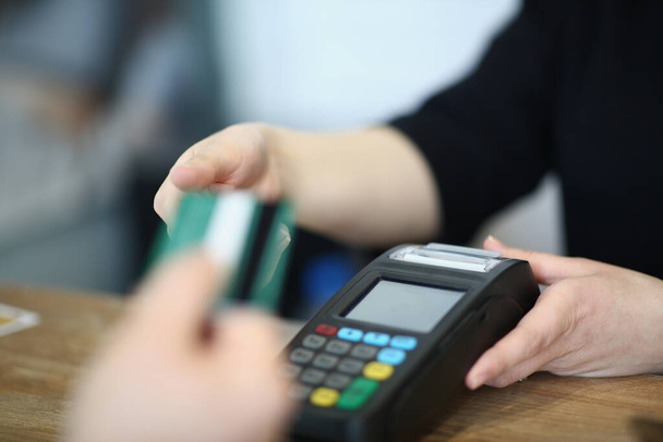 Myyjä tarjoaa ostajalle maksaa ostaa luottokortilla. Tavaroiden maksaminen maksupäätteen kautta - Valokuva, kuva