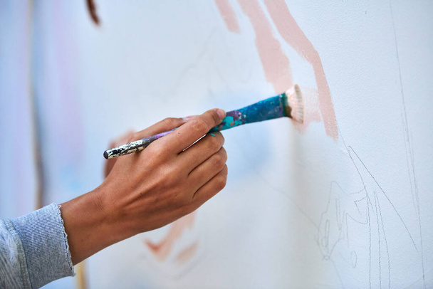 Main d'artiste tient un pinceau et dessine image abstraite surréaliste sur toile blanche au festival de peinture d'art en plein air, peinture processus d'image d'art. Artiste peint tableau atmosphérique - Photo, image