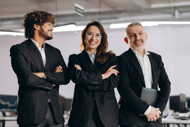 Laughing office workers in black suits having fun together. Successful business team in office. Group of businesspeople expressing positive emotions. High quality photo - Photo, Image