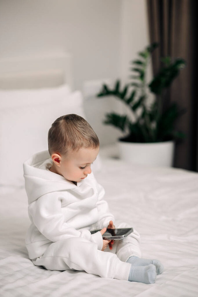 かわいい男の子は部屋の家で電話を使用します。子供はスマートフォンでモバイルゲームをプレイ笑顔と感情を表示 - 写真・画像