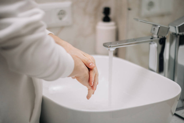 een man met een witte huid wast zijn handen met water close-up in de zomer, huidhygiëne en bescherming tegen coronavirus, wast zijn vingers, stopt de verspreiding van bacteriën, spatten en druppels vliegen bokeh - Foto, afbeelding