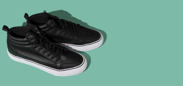 Black shoes on a blue background top view with shadow. Accessories concept. New leather spring shoes. Classic sport style. Fashion shoe. Flat minimalistic store advertising. Footwear Copy space banner - 写真・画像