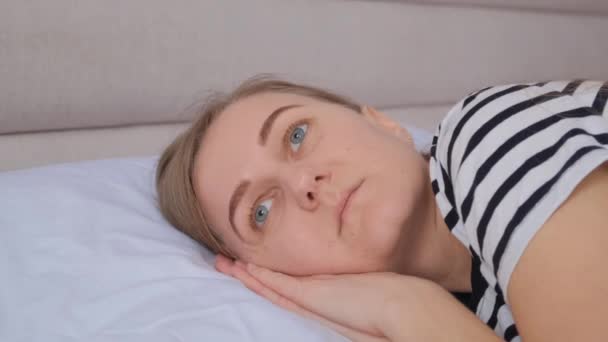 Europejka leżąca w łóżku z powodu zmęczenia pracą cierpi na bezsenność. Kobieta jest zmęczona, przygnębiona.. - Materiał filmowy, wideo