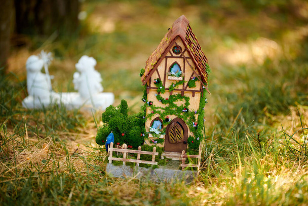 フロント芝生の上の小さな人形の家、緑の芝生のフィールドにかわいい小さな装飾的な家、環境の概念。緑の芝生の森の小さな人形の家、家の芝生のための魅力的な庭の装飾, - 写真・画像