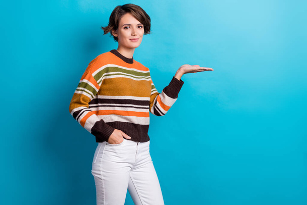 Photo of positive good mood lady wear striped sweater showing arm empty space isolated blue color background. - Foto, Imagen