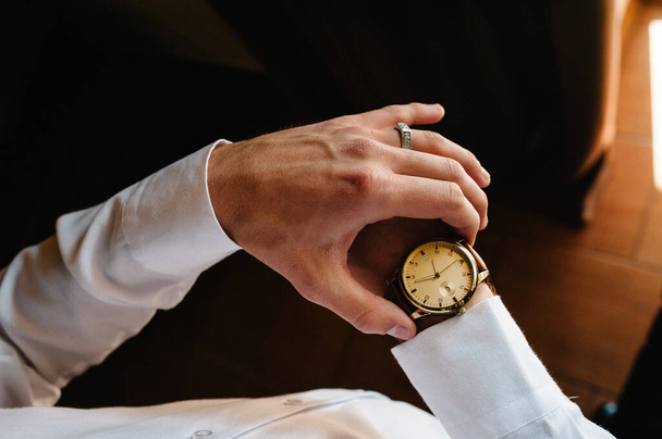 A man in a shirt adjusts the watch on his arm. Close up of businessman using watch. flat lay. top view. - Photo, Image